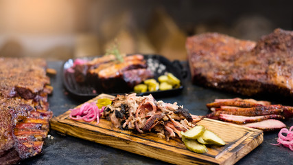 Grill restaurant. Closeup of smoked pulled pork served with pickles on wooden board. Roasted meat...