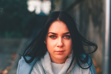 Beautiful girl on the street sits in a coat. Green eyes. Autumn coat