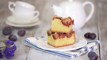 Two pieces of homemade plum cake on wooden table.