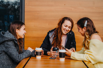 Meeting of three girlfriends in a cafe in the fall