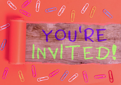 Text sign showing You Re Invited. Business photo text make a polite friendly request to someone go somewhere Paper clip and torn cardboard placed above a wooden classic table backdrop