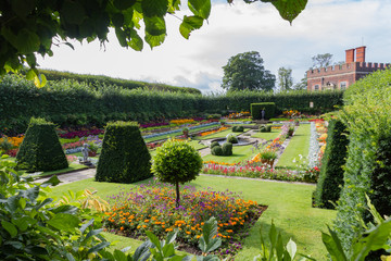 Hampton Court Palace sunken gardens framed by green bushes seen with William III Banqueting House...