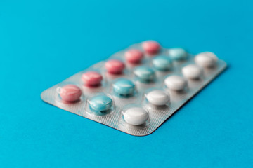 sealed blister of colored pills on a blue background. Medical concept