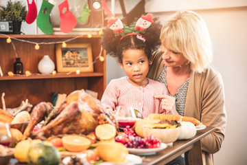 Little Girl Eating  and smile Thanksgiving Celebration Concept. grandmother and granddaughter eating  and smile  at freshly prepared turkey for thanksgiving dinner.