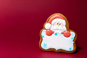 gingerbread cookie of Santa portrait with copyspace on red background. Traditional Christmas food. Christmas and New Year holiday concept.