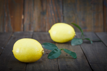 Fresh lemons with leaves on wooden background.Two ripe, juicy lemons.