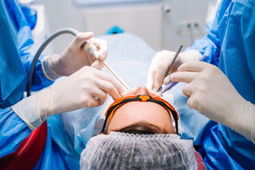 Dentist in uniform perform dental treatment on a patient at modern stomatology office. Selective...