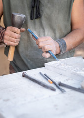 man's hands working with hammer and chisel in craft workshop.