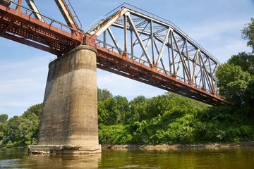 Fototapeta na wymiar Old railway bridge over a river, rusty metal grid