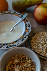 Overview of a breakfast table with granola, oatmeal, yoghurt and fresh fruit. Healthy breakfast ingredients.