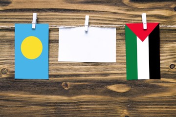 Hanging flags of Palau and Palestine attached to rope with clothes pins with copy space on white...