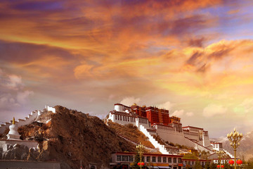 Lateral view of the Potala Palace in Lhasa, Tibet, against a colorful sunset sky covered by...