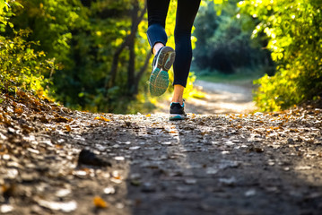 Legs of female runner in motion on a trail in the nature.