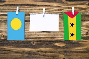 Hanging flags of Palau and Sao Tome And Principe attached to rope with clothes pins with copy space...