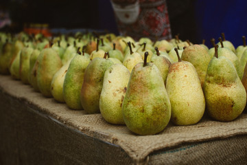 Fresh organic pears background. Ripe yellow large pears in wooden box at farmers market. Pears harvest. Autumn fruit harvest concept. Selective focus