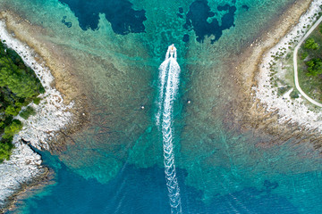 Vertical aerial image of motor boat passing strait close to the coast on the island of Losinj (...