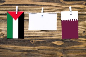Hanging flags of Palestine and Qatar attached to rope with clothes pins with copy space on white...