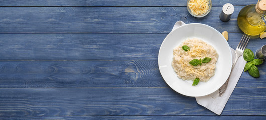 Plate with tasty risotto on wooden table with space for text