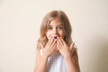 Surprised little girl on light background