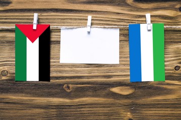 Hanging flags of Palestine and Sierra Leone attached to rope with clothes pins with copy space on...