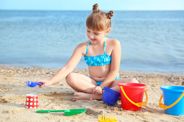 Little girl playing with sand on sea beach