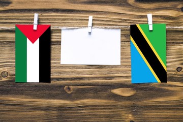 Hanging flags of Palestine and Tanzania attached to rope with clothes pins with copy space on white...