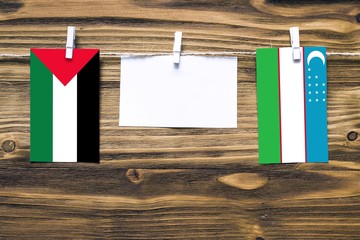 Hanging flags of Palestine and Uzbekistan attached to rope with clothes pins with copy space on...