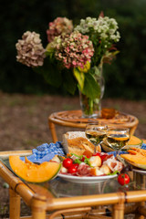 Delicious snacks for romantic dinner for a couple. Wine, fruits, light food. Beautiful table decor, bright colors. Outside, closeup