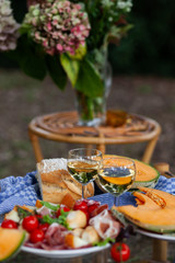 Delicious snacks for romantic dinner for a couple. Wine, fruits, light food. Beautiful table decor, bright colors. Outside, closeup