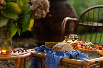 Delicious snacks for romantic dinner for a couple. Wine, fruits, light food. Beautiful table decor, bright colors. Outside, closeup