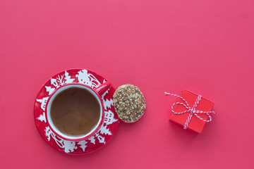 Coffee in Christmas cup, cookie and gift box on a red background top view