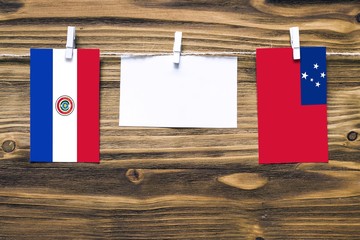 Hanging flags of Paraguay and Samoa attached to rope with clothes pins with copy space on white...