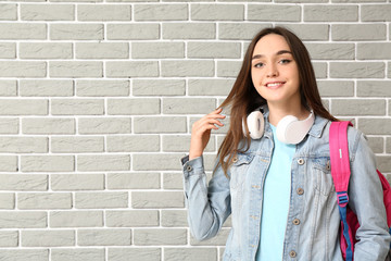 Beautiful female student on brick background