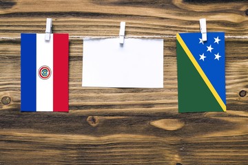 Hanging flags of Paraguay and Solomon Islands attached to rope with clothes pins with copy space on...