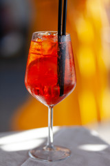 Traditional italian summer drink: aperol spritz with prosecco wine. Served with black straw, slice of orange and ice. Refreshing cocktail for summer party. Vacations mode on. Contrast day light