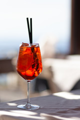 Traditional italian summer drink: aperol spritz with prosecco wine. Served with black straw, slice of orange and ice. Refreshing cocktail for summer party. Vacations mode on. Contrast day light