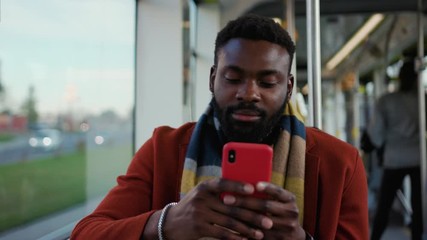 Close up serious portrait african american man use smartphone sitting in tram traffic typing handsome passangers stylish transportation using way internet online texting guy slow motion - Powered by Adobe