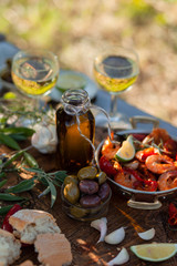 Romantic italian lunch outside of a couple: copper pan with delicious and spicy fried shrimps with herbs and garlic, wine, olives. Luxury lifestyle, gourmet food