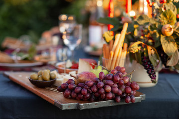 Dinner party outside to celebrate special occasion. Light snacks, fruit, cheese. Red candles as decor. Relax atmosphere, festive mood