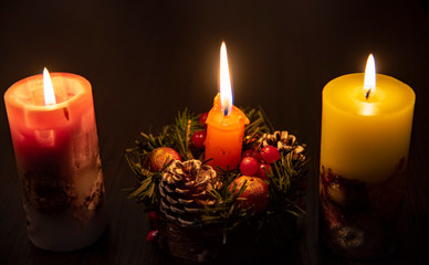 Three burning Christmas candles on a dark background.