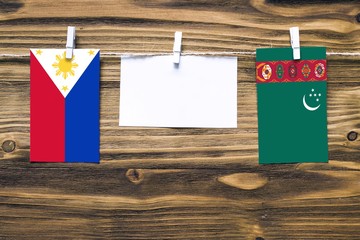 Hanging flags of Philippines and Turkmenistan attached to rope with clothes pins with copy space on...
