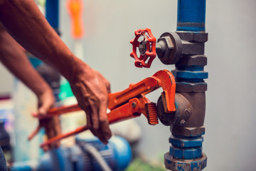 Plumber using a wrench to repair and remove the water supply pipe and valve. Plumbers working using...