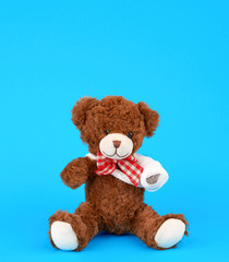 brown teddy bear with rewound white bandage paw on a blue background