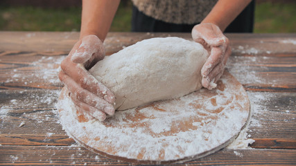 Obraz premium A young woman kneads the dough with her hands and puts it into the mold. Homemade bread baking.