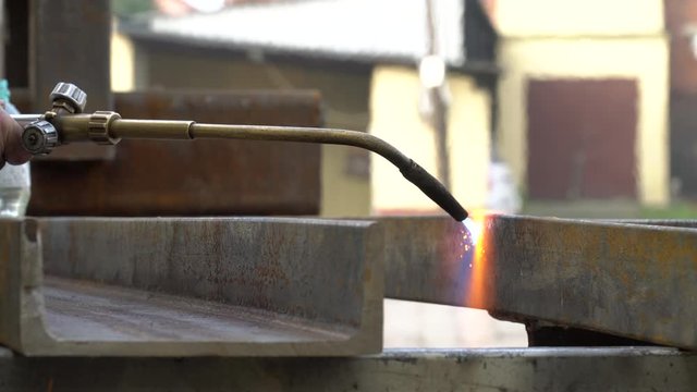 Cutting a steel profile with an acetylene torch. Worker gently heating a steel element with a cutting torch.