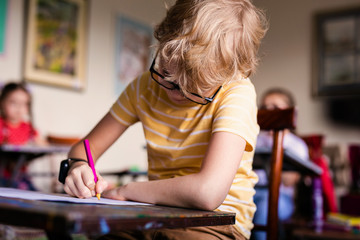 Blonde boy with glasses drawing. Group of elementary school pupils in classroom on art class. Russia, Krasnodar, May, 23, 2019 - obrazy, fototapety, plakaty