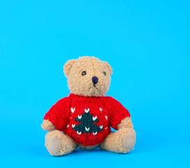 traditional toy teddy bear dressed in a red knitted sweater sits
