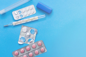 pills and thermometer on blue background