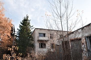 old brick house with balcony and trees in Chernobyl