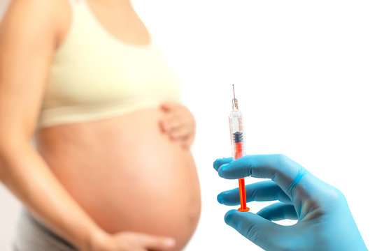 Doctor hand preparing to injects anticoagulants into pregnant woman belly, isolated on white background